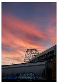 a train traveling under a bridge at sunset