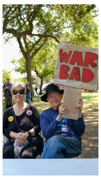 a couple holding a sign that says war bad