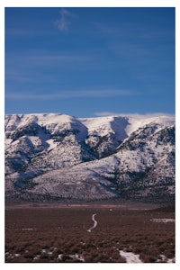 a snow covered mountain range with a dirt road in the background